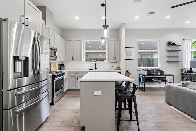4510 Vernon St, Houston, TX 77020 - kitchen with appliances with stainless steel finishes, a breakfast bar, backsplash, light countertops, and a center island