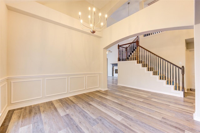 22934 Cove Timbers Ct, Tomball, TX 77375 - empty room with arched walkways, a towering ceiling, wood finished floors, stairs, and a chandelier
