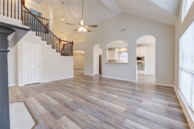 22934 Cove Timbers Ct, Tomball, TX 77375 - unfurnished living room with a ceiling fan, healthy amount of natural light, arched walkways, high vaulted ceiling, and light wood-style floors