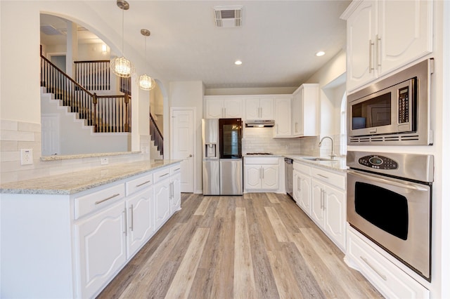 22934 Cove Timbers Ct, Tomball, TX 77375 - kitchen with appliances with stainless steel finishes, backsplash, under cabinet range hood, white cabinets, and recessed lighting