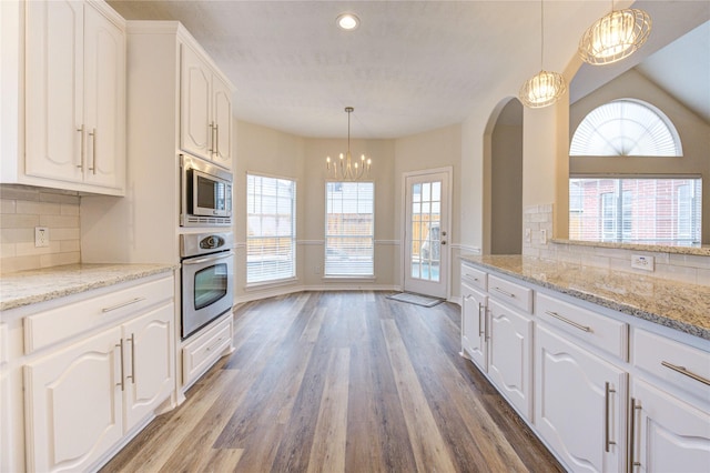 22934 Cove Timbers Ct, Tomball, TX 77375 - kitchen featuring appliances with stainless steel finishes, a chandelier, white cabinetry, wood finished floors, and decorative backsplash