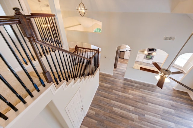22934 Cove Timbers Ct, Tomball, TX 77375 - stairway featuring arched walkways, wood finished floors, a chandelier, a towering ceiling, and ceiling fan