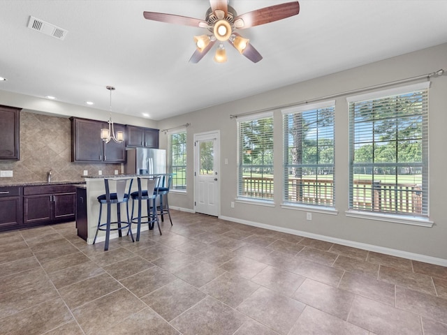 16020 Fountainview Dr Unit 21, Montgomery, TX 77356 - kitchen featuring tasteful backsplash, a breakfast bar area, a center island, dark brown cabinets, and ceiling fan