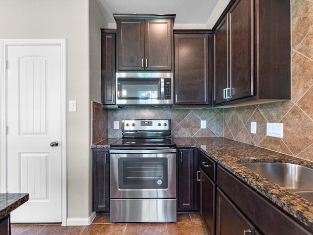 16020 Fountainview Dr Unit 21, Montgomery, TX 77356 - kitchen featuring appliances with stainless steel finishes, dark brown cabinets, backsplash, dark stone counters, and tile patterned flooring