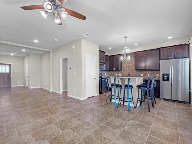 16020 Fountainview Dr Unit 21, Montgomery, TX 77356 - kitchen featuring stainless steel appliances, dark brown cabinetry, tasteful backsplash, a ceiling fan, and a breakfast bar