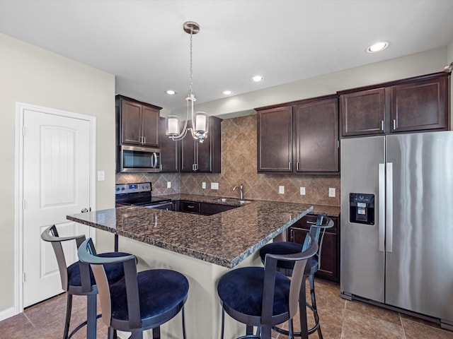 16020 Fountainview Dr Unit 21, Montgomery, TX 77356 - kitchen featuring appliances with stainless steel finishes, dark brown cabinetry, a breakfast bar, a chandelier, and decorative backsplash