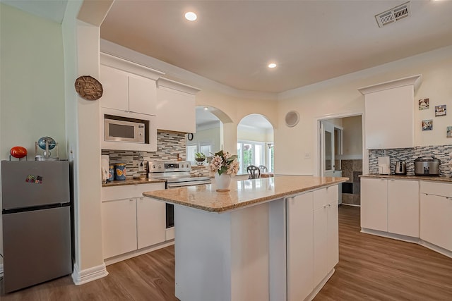 1407 Ella Cir, Houston, TX 77090 - kitchen with stainless steel appliances, decorative backsplash, white cabinetry, wood finished floors, and a center island