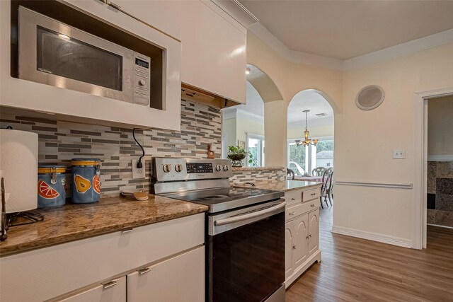 1407 Ella Cir, Houston, TX 77090 - kitchen featuring appliances with stainless steel finishes, crown molding, arched walkways, white cabinetry, and decorative backsplash
