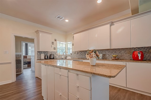 1407 Ella Cir, Houston, TX 77090 - kitchen featuring wood finished floors, a center island, white cabinets, backsplash, and recessed lighting