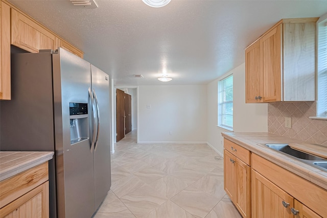 1640 Shepherd St, Hempstead, TX 77445 - kitchen with stainless steel refrigerator with ice dispenser, light brown cabinetry, light countertops, and decorative backsplash