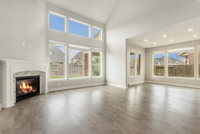 28622 Mountain Timber Ct, Fulshear, TX 77441 - unfurnished living room with a stone fireplace, healthy amount of natural light, wood finished floors, recessed lighting, and high vaulted ceiling