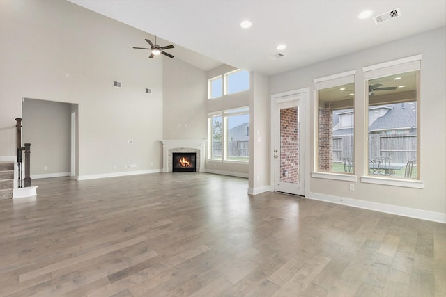 28622 Mountain Timber Ct, Fulshear, TX 77441 - unfurnished living room with a ceiling fan, a lit fireplace, wood finished floors, recessed lighting, and stairway
