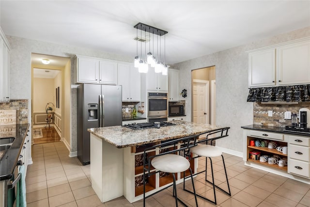 14419 Timbergreen Dr, Magnolia, TX 77355 - kitchen featuring appliances with stainless steel finishes, light tile patterned flooring, a kitchen bar, and white cabinetry