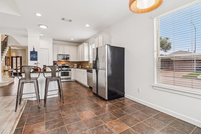 4003 Autumn Pines Trl, Houston, TX 77084 - kitchen with appliances with stainless steel finishes, a kitchen breakfast bar, dark countertops, backsplash, and white cabinetry