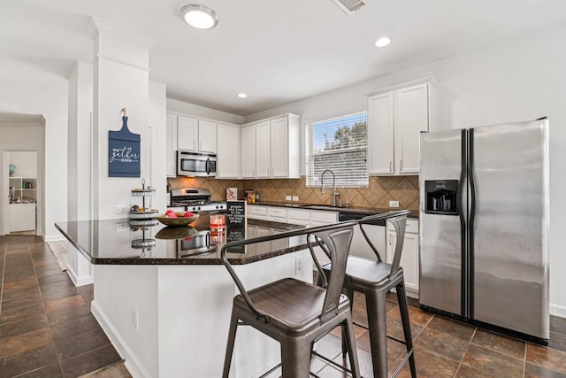 4003 Autumn Pines Trl, Houston, TX 77084 - kitchen with stainless steel appliances, dark countertops, white cabinets, decorative backsplash, and a breakfast bar