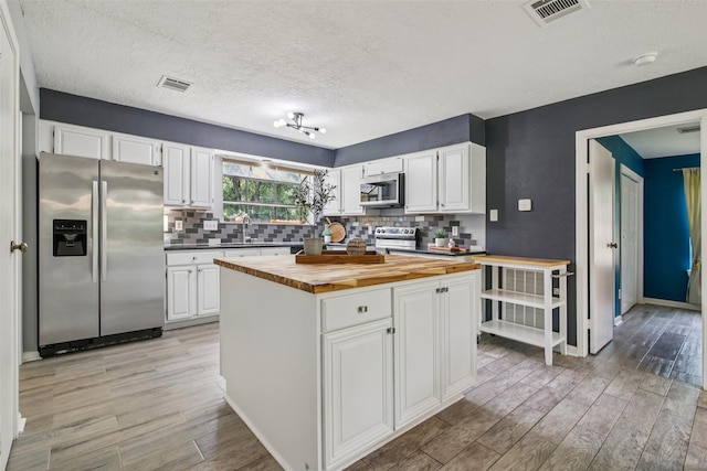 5210 Creek Shadows Dr, Houston, TX 77339 - kitchen featuring stainless steel appliances, wood counters, light wood-style floors, backsplash, and a textured ceiling