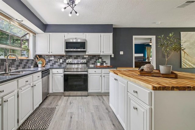 5210 Creek Shadows Dr, Houston, TX 77339 - kitchen with stainless steel appliances, wood counters, light wood-style flooring, and white cabinetry