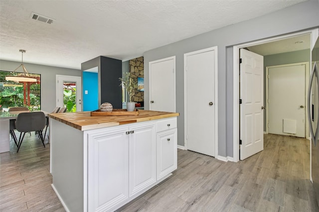 5210 Creek Shadows Dr, Houston, TX 77339 - kitchen featuring wood counters, white cabinetry, light wood-style flooring, decorative light fixtures, and a kitchen island