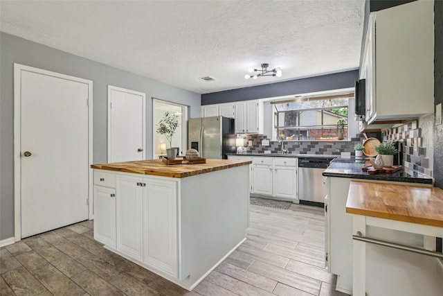 5210 Creek Shadows Dr, Houston, TX 77339 - kitchen featuring wooden counters, appliances with stainless steel finishes, decorative backsplash, white cabinets, and a kitchen island