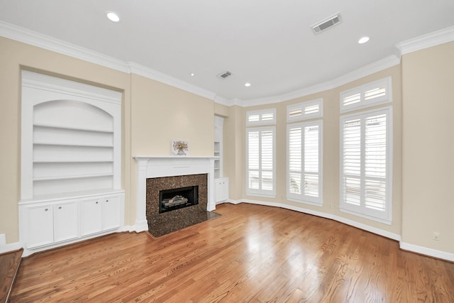 2930 Brompton Square Dr, Houston, TX 77025 - unfurnished living room featuring light wood-style flooring, ornamental molding, a premium fireplace, recessed lighting, and built in shelves