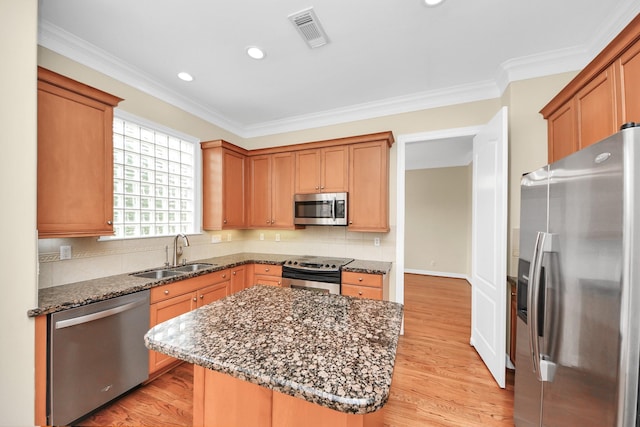 2930 Brompton Square Dr, Houston, TX 77025 - kitchen with stainless steel appliances, dark stone countertops, light wood-style flooring, decorative backsplash, and ornamental molding