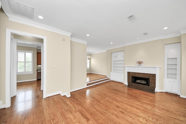 2930 Brompton Square Dr, Houston, TX 77025 - unfurnished living room with light wood-style floors, a premium fireplace, a chandelier, crown molding, and built in shelves