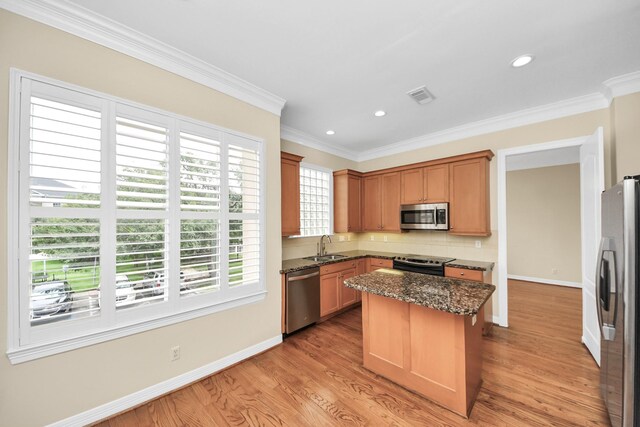 2930 Brompton Square Dr, Houston, TX 77025 - kitchen featuring stainless steel appliances, light wood finished floors, dark stone countertops, a kitchen island, and decorative backsplash
