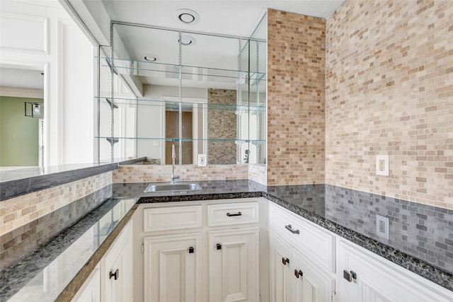 12102 Moorcreek Dr, Houston, TX 77070 - kitchen featuring backsplash, dark stone countertops, and white cabinets