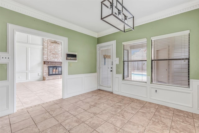 12102 Moorcreek Dr, Houston, TX 77070 - unfurnished dining area with ornamental molding, a decorative wall, a fireplace, a wainscoted wall, and light tile patterned flooring