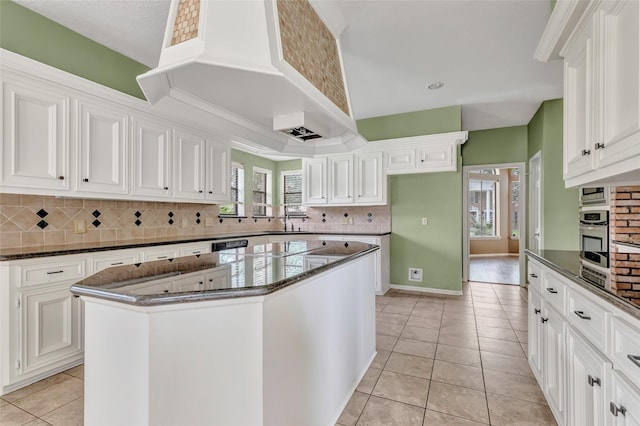 12102 Moorcreek Dr, Houston, TX 77070 - kitchen with light tile patterned floors, backsplash, a center island, dark stone countertops, and white cabinetry