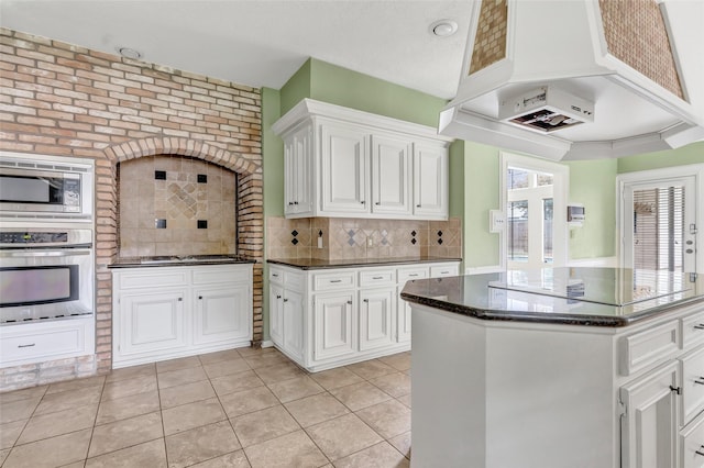 12102 Moorcreek Dr, Houston, TX 77070 - kitchen featuring appliances with stainless steel finishes, light tile patterned floors, decorative backsplash, white cabinets, and dark stone counters