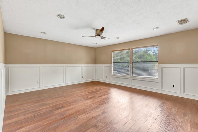 12102 Moorcreek Dr, Houston, TX 77070 - spare room with a decorative wall, a ceiling fan, wainscoting, wood finished floors, and a textured ceiling