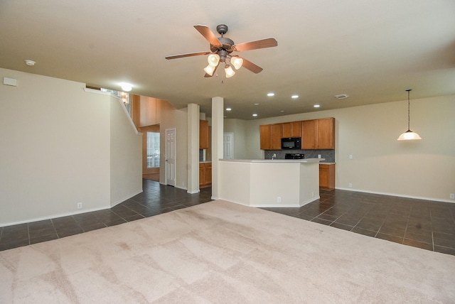2814 Edgewick Elm St, Fresno, TX 77545 - kitchen with black microwave, dark tile patterned floors, brown cabinetry, ceiling fan, and open floor plan
