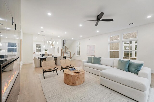 5405 Dickson St, Houston, TX 77007 - living room featuring stairs, light wood-type flooring, recessed lighting, a ceiling fan, and a chandelier