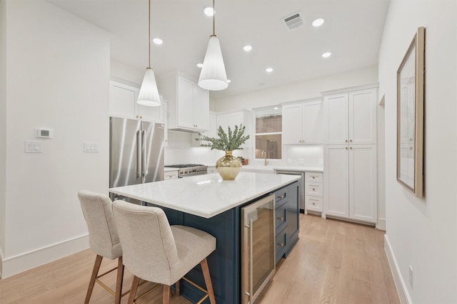 5405 Dickson St, Houston, TX 77007 - kitchen with wine cooler, freestanding refrigerator, white cabinets, light wood finished floors, and a breakfast bar area