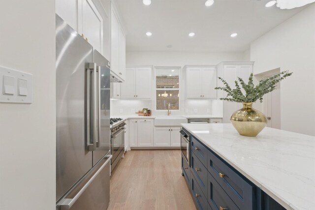 5405 Dickson St, Houston, TX 77007 - kitchen with high end appliances, white cabinetry, light wood finished floors, light stone countertops, and recessed lighting