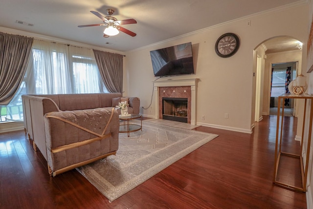 17803 Inland Oaks Dr, Richmond, TX 77407 - living room featuring arched walkways, a ceiling fan, wood finished floors, ornamental molding, and a fireplace