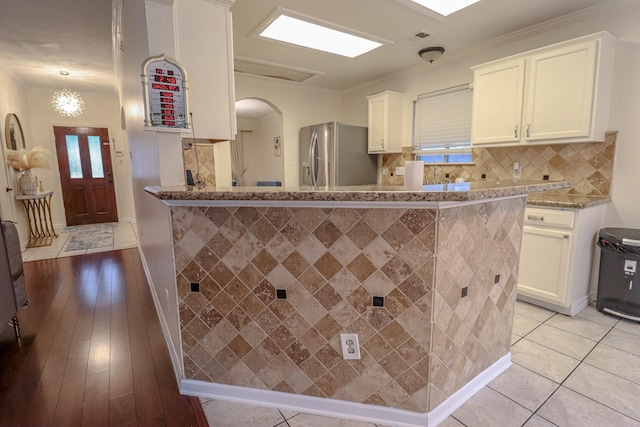 17803 Inland Oaks Dr, Richmond, TX 77407 - kitchen featuring stainless steel refrigerator with ice dispenser, white cabinets, light stone countertops, arched walkways, and crown molding