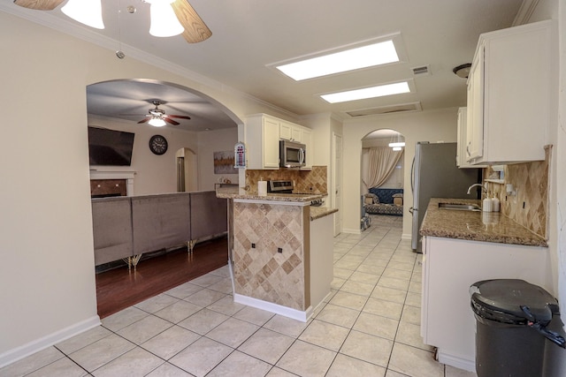 17803 Inland Oaks Dr, Richmond, TX 77407 - kitchen with stainless steel appliances, a ceiling fan, arched walkways, white cabinets, and backsplash