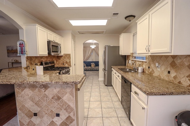 17803 Inland Oaks Dr, Richmond, TX 77407 - kitchen with appliances with stainless steel finishes, arched walkways, white cabinets, light stone countertops, and ornamental molding