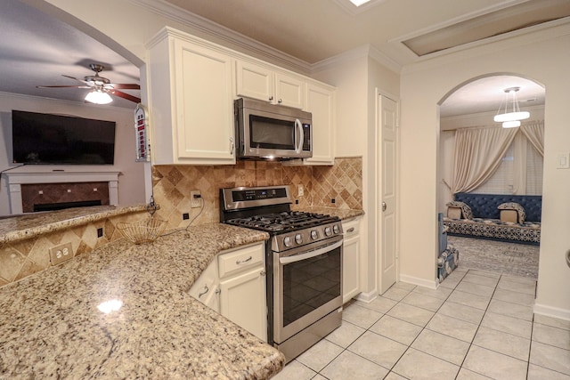 17803 Inland Oaks Dr, Richmond, TX 77407 - kitchen featuring appliances with stainless steel finishes, arched walkways, ornamental molding, light stone countertops, and light tile patterned floors