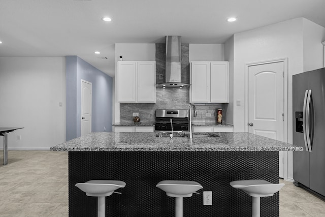 14205 Dream Rd, New Caney, TX 77357 - kitchen featuring appliances with stainless steel finishes, wall chimney range hood, a breakfast bar area, stone counters, and recessed lighting