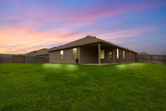 14205 Dream Rd, New Caney, TX 77357 - back of house at dusk featuring a fenced backyard, a patio area, and brick siding