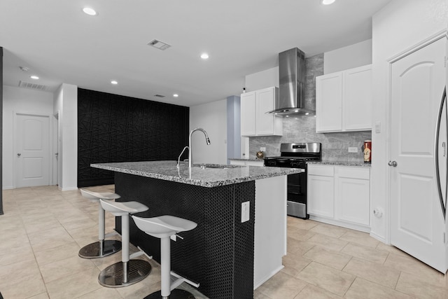 14205 Dream Rd, New Caney, TX 77357 - kitchen with wall chimney exhaust hood, gas range, a kitchen bar, light stone countertops, and recessed lighting