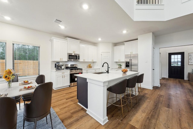 390 Kendall Crest Dr, Alvin, TX 77511 - kitchen featuring appliances with stainless steel finishes, white cabinetry, a kitchen breakfast bar, a kitchen island with sink, and recessed lighting