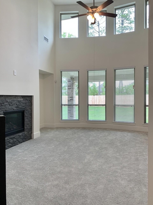 12515 Tullich Run Dr, Humble, TX 77346 - unfurnished living room featuring a high ceiling, ceiling fan, carpet floors, and a stone fireplace