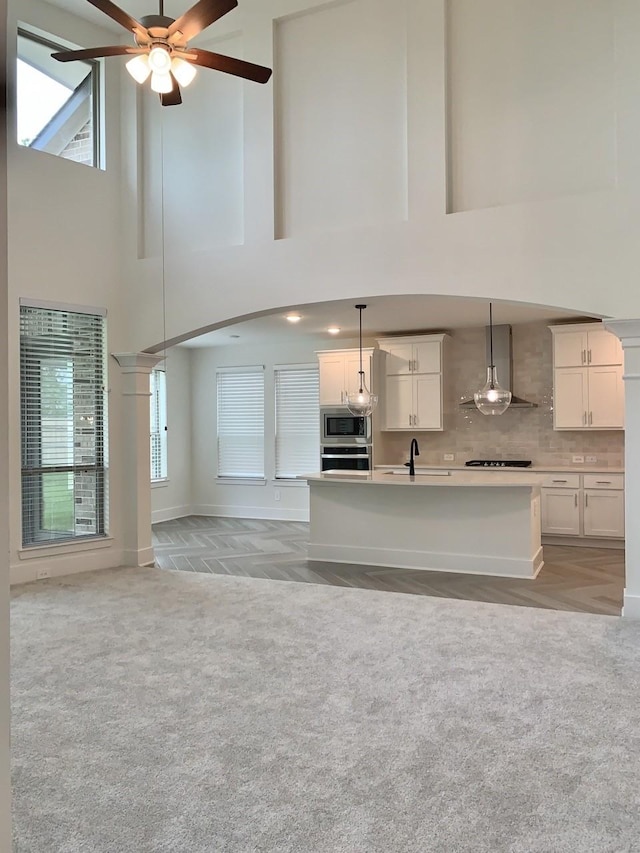 12515 Tullich Run Dr, Humble, TX 77346 - kitchen with wall chimney exhaust hood, stainless steel appliances, a high ceiling, light colored carpet, and hanging light fixtures
