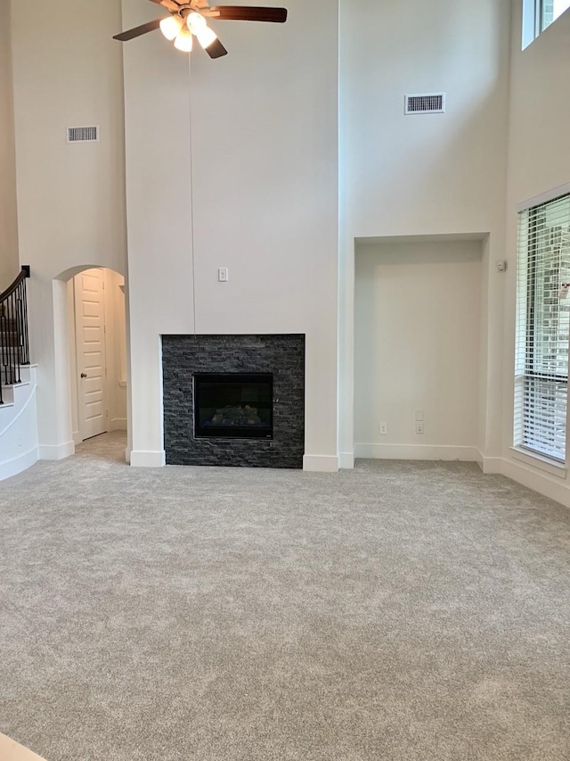 12515 Tullich Run Dr, Humble, TX 77346 - unfurnished living room with a towering ceiling, a ceiling fan, carpet, a fireplace, and arched walkways