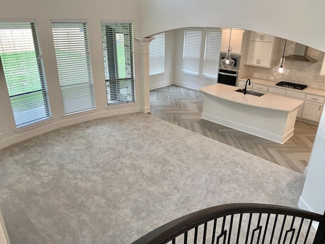 12515 Tullich Run Dr, Humble, TX 77346 - kitchen with appliances with stainless steel finishes, light countertops, wall chimney range hood, decorative backsplash, and a center island with sink