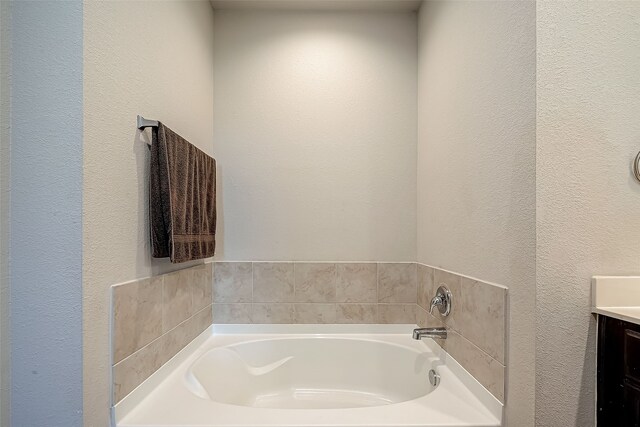 18623 Swainboro Dr, New Caney, TX 77357 - bathroom with a textured wall, a bath, and vanity